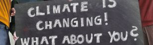 Die Abbildung zeigt junge Menschen, die ein Schild halten, auf dem steht “Climate ist Changing! What about you?“
